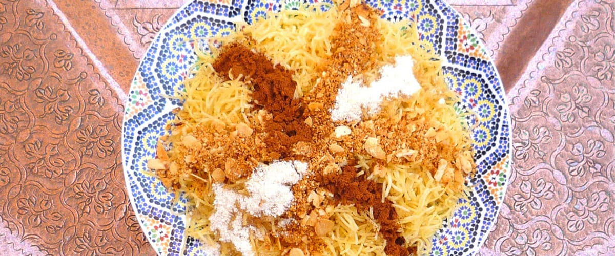 Recipe to make Moroccan Pasta with Almonds, Cinnamon and Culinary Argan Oil photo of plate of moroccan seffa pasta crossed with powdered cinnamon, sugar, almonds of 1 meter wide engraved copper moroccan plate
